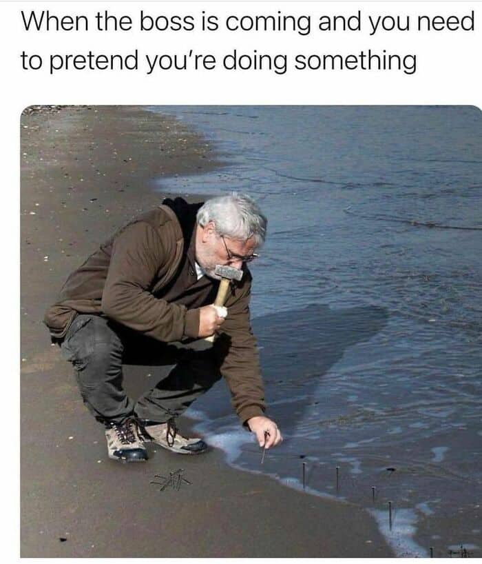 image of man hammering nails into the sand on a beach with text that says "When the boss is coming and you need to pretend you're doing something."