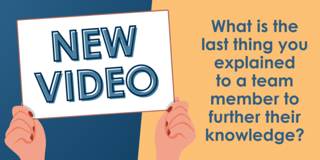 Person holding a sign that reads "new video" with a question "what is the last thing you explained to a team member to further their knowledge?" on a yellow background.