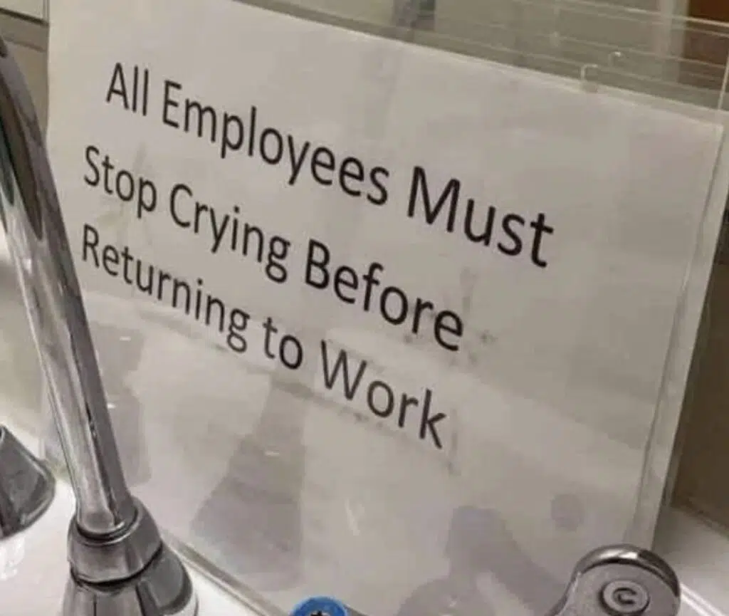 A sign reading "all employees must stop crying before returning to work" displayed at a workplace.