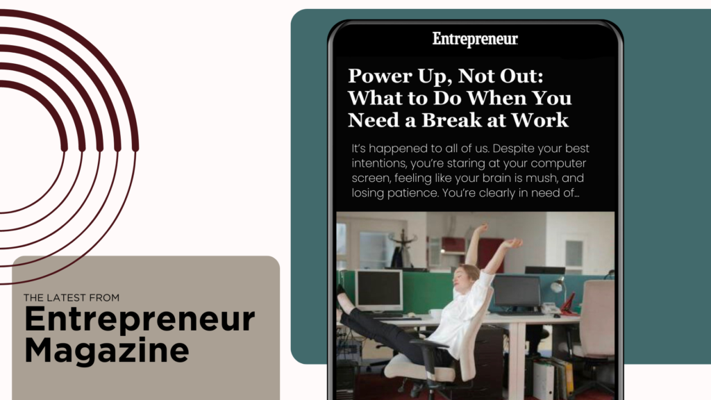 A person reclining in an office chair with feet up on the desk, in front of a computer screen displaying an article titled "Power Up, Not Out: What to Do When You Need a Break at Work" from Entrepreneur magazine.