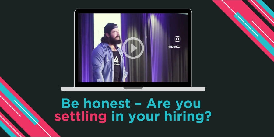 A laptop screen shows a paused video of a man speaking on stage. Text below reads, "Be honest – Are you settling in your hiring?" with a social media handle displayed on the right side.