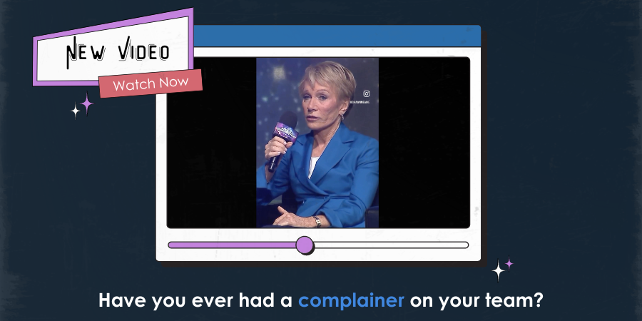 A woman in a blue suit speaks into a microphone on a video screen. Caption reads, "Have you ever had a complainer on your team?.