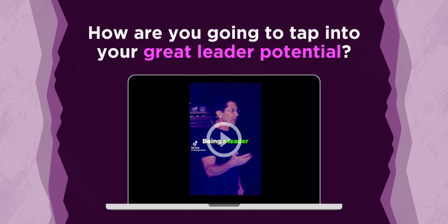 A laptop screen displaying a video paused on a man speaking, with text above saying "How are you going to tap into your great leader potential?" on a purple background.