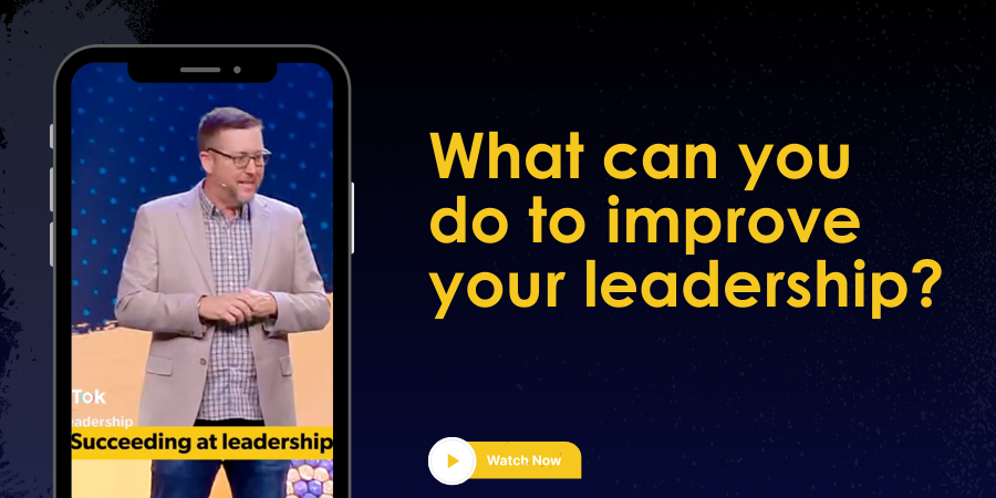 A man speaking on stage is shown on a smartphone screen. The text reads, "What can you do to improve your leadership?" and "Succeeding at leadership." A "Watch Now" button is also visible.